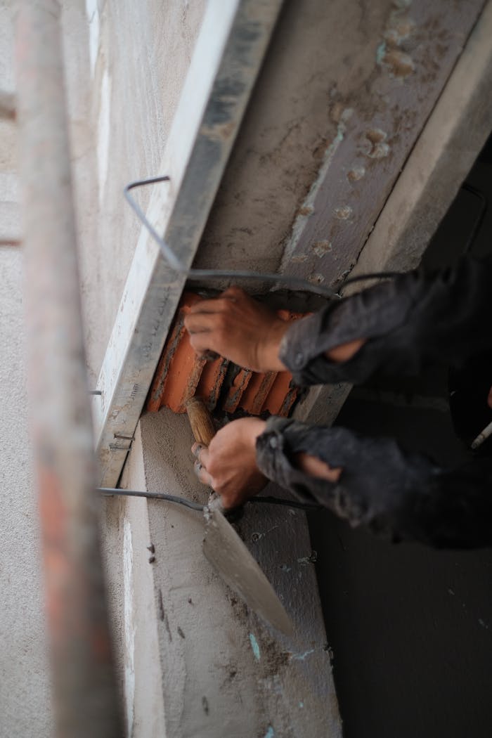 gallery-6 Worker repairing structure with trowel, showcasing detailed craftsmanship.