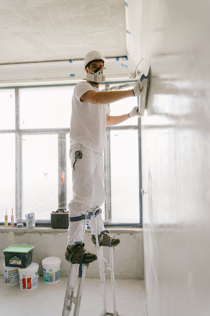 why-choose-us Construction worker smoothing a wall indoors using safety gear.