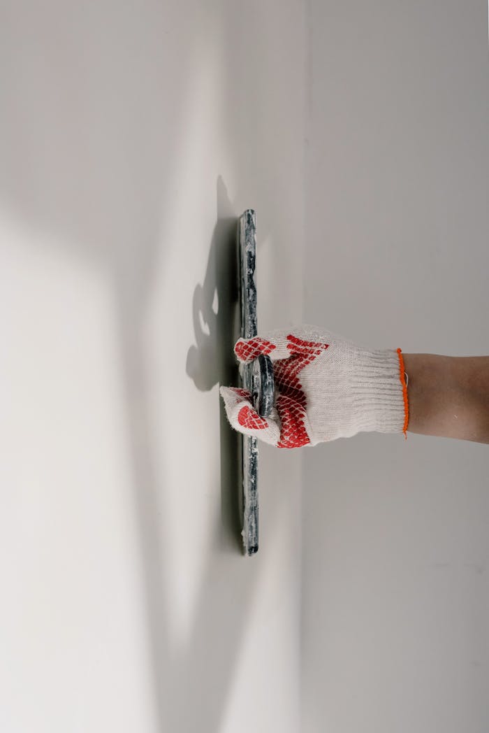 gallery-3 Crop anonymous painter in gloves preparing wall for painting works during renovation process in apartment