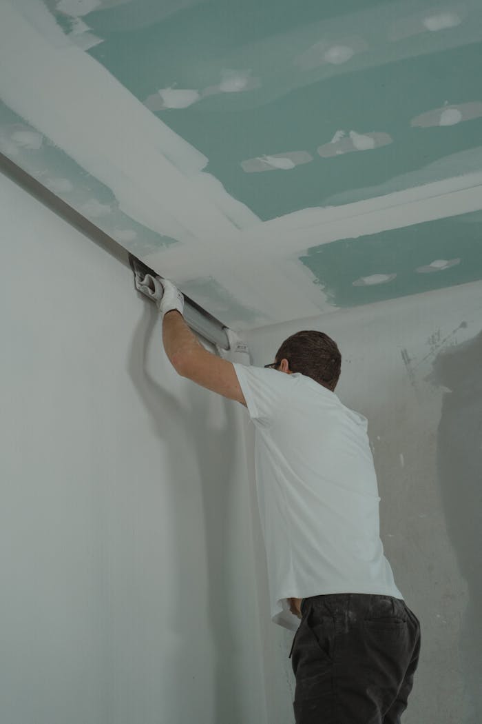 gallery-1 A man works meticulously on drywall installation during a house renovation.