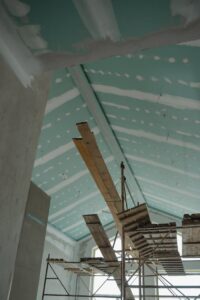 Home Scaffolding setup in an interior construction space with suspended ceiling boards and wooden planks.