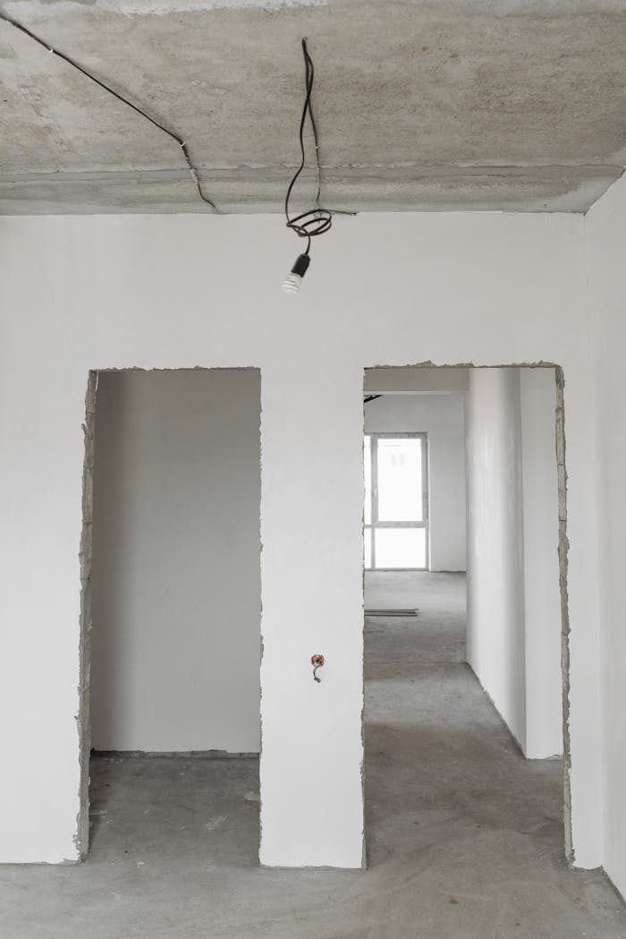 services-01 Unfinished room interior with white plastered walls and exposed ceiling in a construction site.